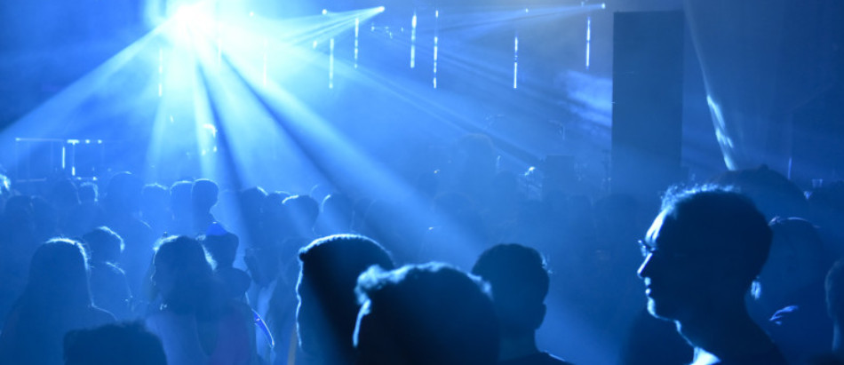 A crowd of people are lit by rays of bright blue light.