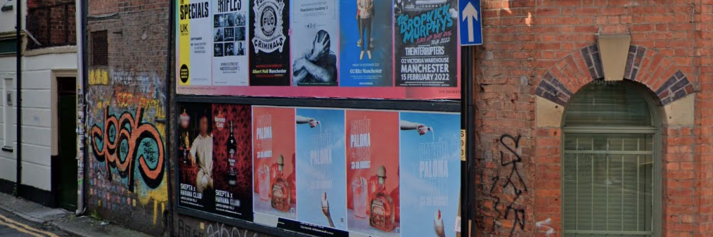 A billboard site on a red brick building with a street sign reading Carpenters Lane